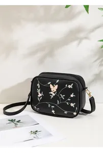 Close-up of butterfly and flower embroidery on black PU leather camera crossbody bag