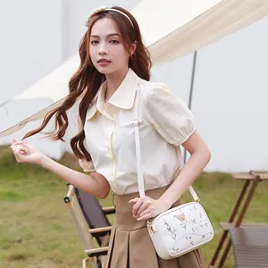 White crossbody camera bag with pink floral butterfly embroidery and thin shoulder strap
