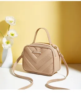 Detailed close-up of beige V-quilted small square bag with metallic logo and zipper