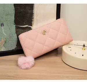 Detail of pink quilted long wallet featuring metal flower ornament and fluffy pompom charm