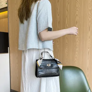 Black crocodile embossed crossbody bag with chain strap and scarf-wrapped handle decor