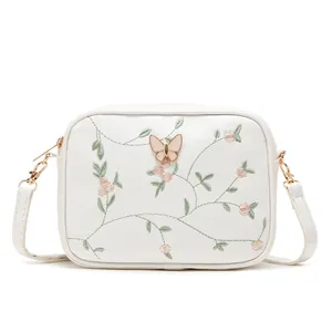 White crossbody camera bag with floral embroidery and golden butterfly clasp detail