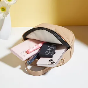 Beige round crossbody bag with V-quilted pattern showing internal storage for cosmetics