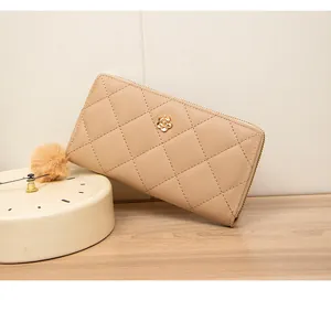 Detail of beige quilted long wallet with a golden camellia flower metal buckle on wood