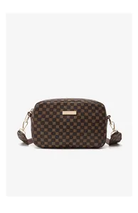 Detail of crossbody camera bag with retro dark brown pattern and golden logo plate