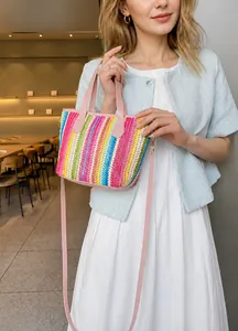 Detalle del mini bolso tejido a rayas arcoíris con asa y correa de cuero rosa