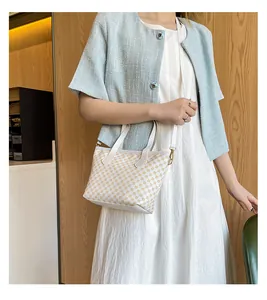 Detalle del bolso bandolera crema con círculos amarillos sobre abrigo azul claro en modelo