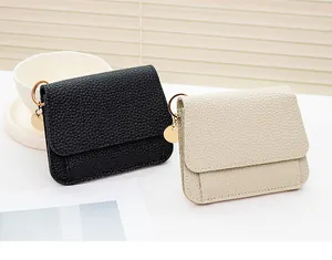 Dettaglio di mini portamonete in pelle a grana litchi neri e beige con ciondoli dorati