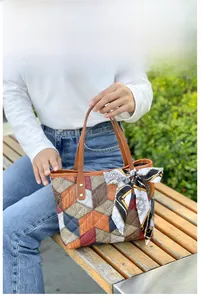 Detail of color-block geometric tote bag with brown handles and decorative silk scarf
