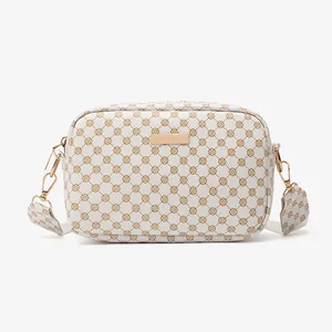 White crossbody camera bag with brown geometric heart pattern and golden hardware