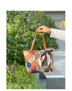 Detailed view of a multi-color patchwork tote bag with an elegant silk scarf handle decoration