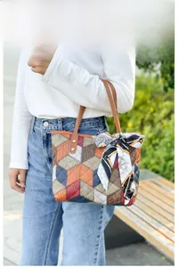 Outdoor model shot showing the patchwork leather tote bag with a silk scarf decoration