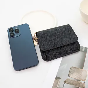 Mini portafoglio in pelle nera martellata con ciondolo dorato accanto a smartphone