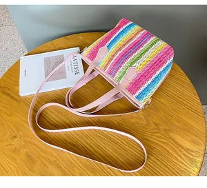 Detalle de bolso tejido de arcoíris colorido con asas rosas sobre una mesa de madera