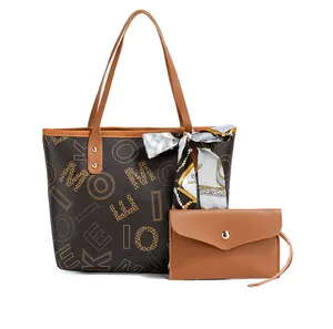 Detail of the brown tote bag with artistic letter print and decorative handle scarf