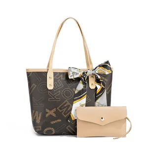 Detail of faux leather tote with letter prints, silk scarf handle, and matching clutch bag