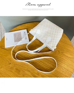 Detalle de bolso blanco con patrones dorados sobre mesa de madera con libro de arte deco