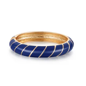 Dettaglio di bracciale placcato oro con strisce di smalto blu e interno in metallo spazzolato