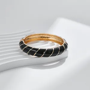 Dettaglio della trama a spirale in smalto nero e cerniera dorata sul bracciale