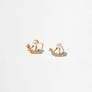 Détail de boucles d'oreilles baroques en or avec perle blanche et accents de zircone