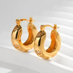 Dettaglio di orecchini a cerchio placcati oro 18K con stella incisa e cristallo zircone
