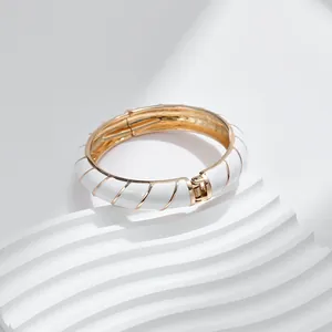 Dettaglio del bracciale rigido in smalto bianco con strisce a spirale dorate e cerniera