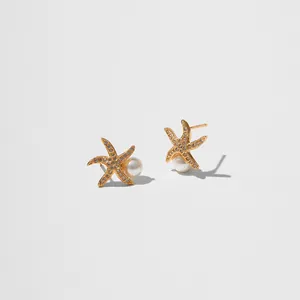 Vue détaillée des boucles d'oreilles étoile de mer dorées avec cristaux et perles blanches