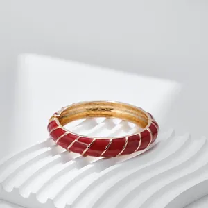 Dettaglio macro del bracciale in smalto rosso con spirali dorate e chiusura a cerniera