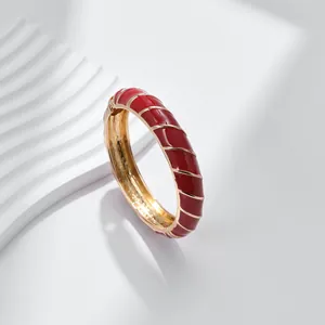Dettaglio del bracciale in smalto rosso con strisce dorate e finitura interna liscia