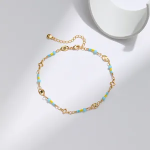 Detalle de la tobillera de latón bañado en oro 18K con dijes de ojo azul y flores finas