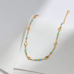 Detalle de tobillera bañada en oro de 18 quilates con cuentas azules y dijes de ojo