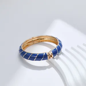 Dettaglio del bracciale a cerniera placcato oro in smalto blu con strisce diagonali