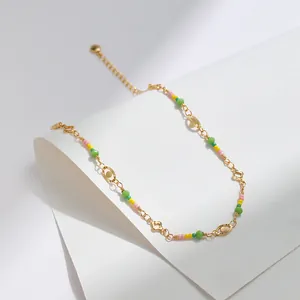 Detalle de tobillera chapada en oro de 18K con cuentas de colores y dijes de flores