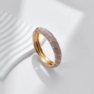 Dettaglio del bracciale a cerniera placcato oro con smalto grigio e motivo a onde