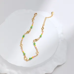 Detalle de una tobillera bañada en oro de 18K con cuentas de colores y dijes de tréboles