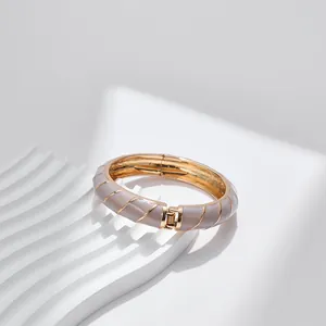 Dettaglio del bracciale a cerniera dorato con smalto grigio e strisce diagonali dorate