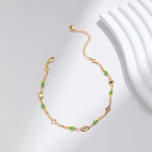 Detalle de tobillera chapada en oro de 18K con cuentas de colores y amuleto de ojo de la suerte