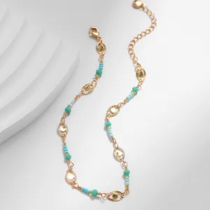 Detalle de tobillera de latón chapado en oro de 18K con cuentas azules y dijes