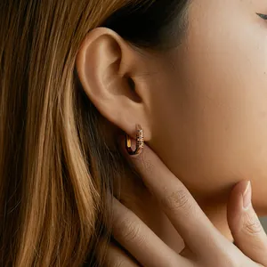 Detail of 18K gold plated U-shaped earrings with colorful zircon pavé worn by a model