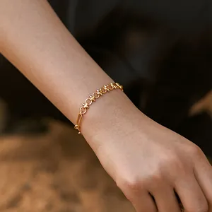Macro detail of the 18K gold plated woven chain bracelet with 3D rivet link design