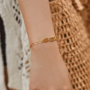 Detail of 18K gold plated chain bracelet on wrist with textured rectangular links