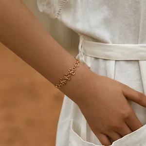Detail of hand-woven 18K gold-plated infinity chain bracelet worn on a female wrist