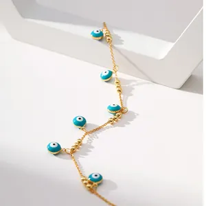 Gros plan détaillé du bracelet de cheville en laiton doré 18K avec breloques œil bleu