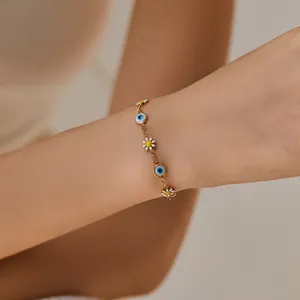 Close-up of 18K gold plated woven bracelet with evil eye beads and daisy charms on wrist