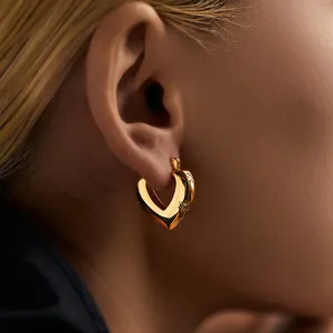 Macro shot of 18K gold plated heart earring with star-set zircon on female ear