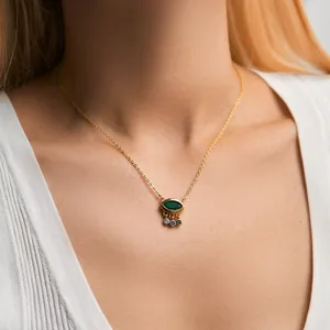 Detail of 18K gold plated necklace with marquise green gem eye pendant and colored crystals