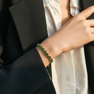 Close-up of elegant leaf-shaped bracelet with green marquise-cut gems on model's wrist