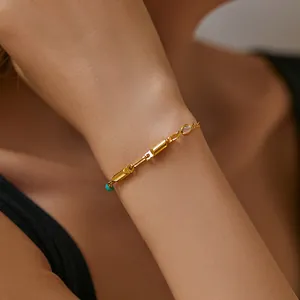 Nahaufnahme eines 18K vergoldeten Armbands mit türkisfarbener Perle und Kristall am Handgelenk