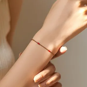 Detail eines 18K vergoldeten minimalistischen Kettenarmbands mit roten Emaille-Akzenten