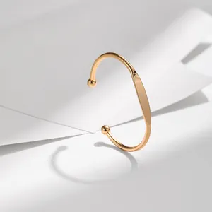 Minimalist gold open cuff bracelet with sleek flat center and polished ball ends on white